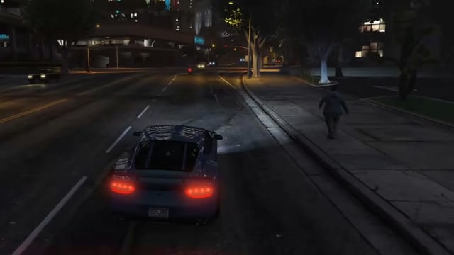 Blue sports car with red tail lights driving down a city street at night, past a man walking on the pavement.