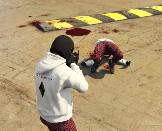 Masked player aiming a rifle at a character lying on the ground beside a pool of blood.