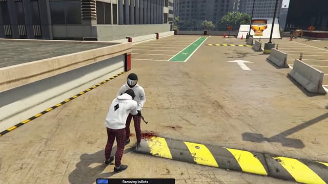 Player in a white hoodie bent over a helmeted player beside a blood stain on a rooftop car park, above a progress bar reading "Removing bullets".