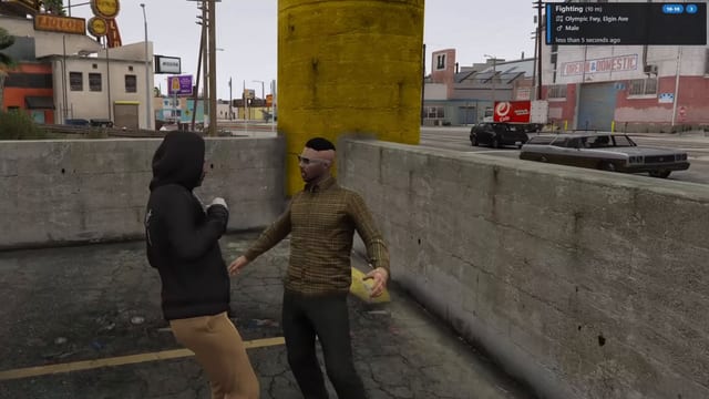Two men fighting beside a yellow pillar on a street, with an alert in the top-right corner: Fighting (10 m), code 10-10, Olympic Fwy, Elgin Ave, Male, less than 5 seconds ago.