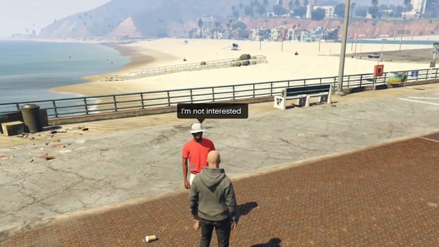 Man in a red shirt and white hat facing the player on a seaside walkway under the speech bubble "I'm not interested", with a beach and hills behind.