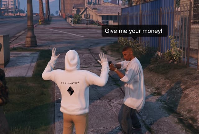On a street pavement, an NPC aims a pistol at a player in a white hoodie with raised hands and says "Give me your money!".