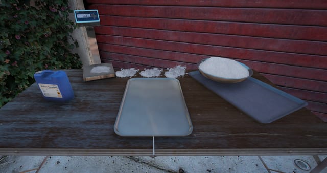 Close-up of an equipment table with trays, powder, a scale and a chemical container.