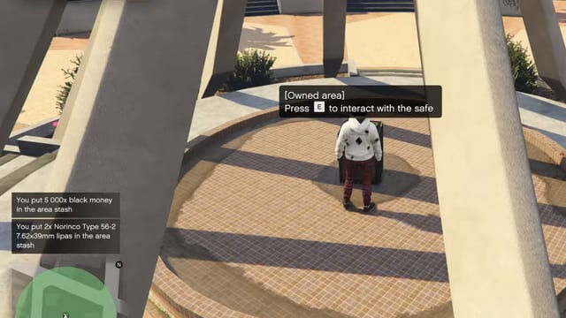Player standing at a safe under a concrete monument with the prompt "[Owned area] Press E to interact with the safe" and two notifications, the first reading "You put 5 000x black money in the area stash".