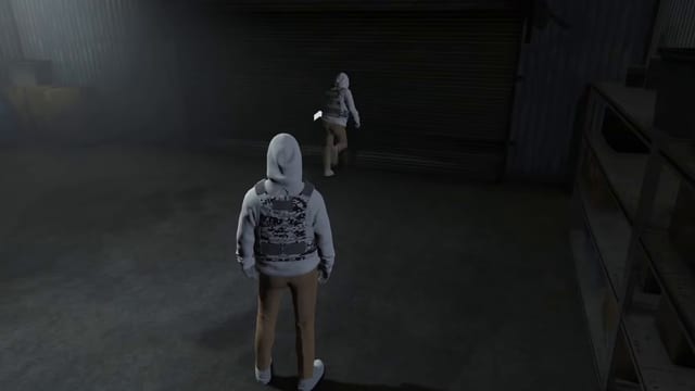 Two hooded players inside a dim garage, one standing in the foreground and one walking in by the closed roller door.