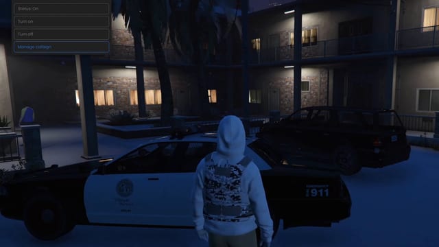 Menu with Status: On, Turn on, Turn off and Manage callsign in the top-left corner, over a snowy motel courtyard at night with a police car and a player in a white hoodie and vest.