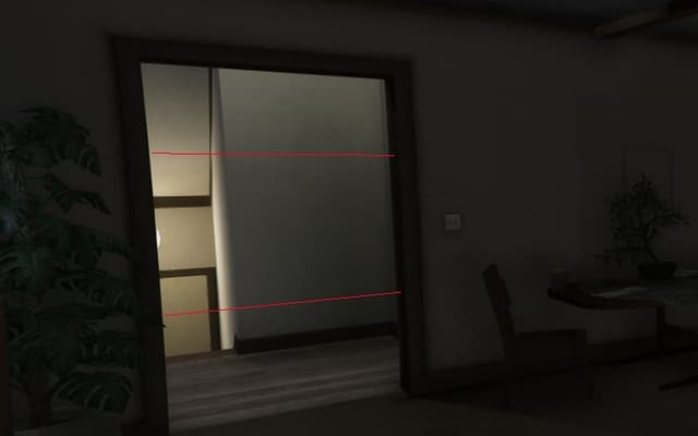 Lit doorway in a dark house with two red laser lines across it, a plant on the left and a table and chair on the right.