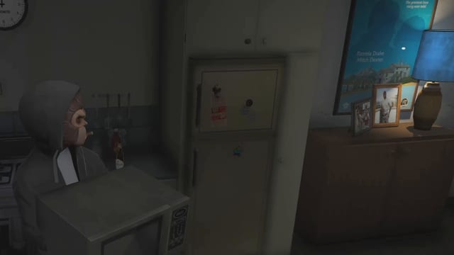 Hooded player in a monkey mask holding a microwave with its door and keypad towards the camera in a dark kitchen, beside a fridge, with framed photos, a film poster and a lit blue lamp on the right.
