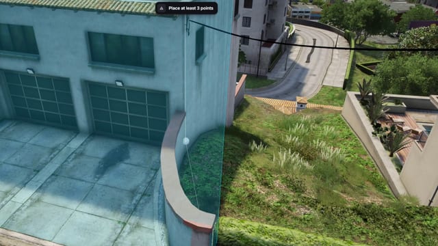 View from above of a house with two garage doors, its forecourt tinted blue up to a vertical blue edge with a white point marker, under the notice "Place at least 3 points".