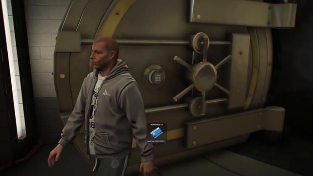 Player in a grey hoodie in front of the round steel vault door and its keypad, beside a keycard item notification.